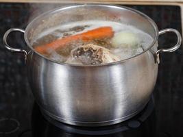 sopa de pollo hirviendo a fuego lento en una olla en la cocina de cerca foto