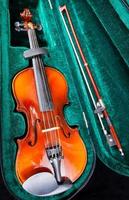 pequeño violín con arco en estuche de terciopelo verde foto