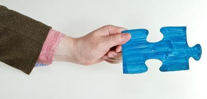 blue painted puzzle piece in male hand photo