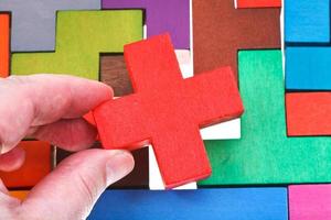 putting cross shaped block in wooden puzzle photo