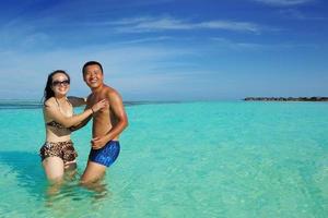 feliz pareja joven disfrutando del verano en la playa foto