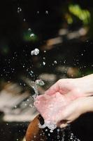 salpicando agua dulce en manos de mujer foto