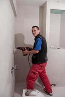construction worker drilling holes in the bathroom photo