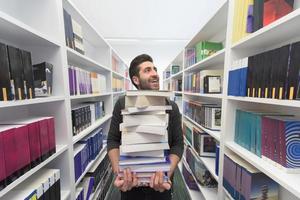 Student holding lot of books in school library photo