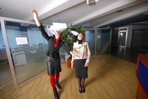 two businesswoman throw papers in office photo