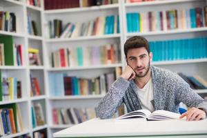 portrait of student while reading book  in school library photo