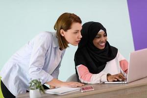 afro muslim  woman  wearing a hijab sits smiling in her home office and using laptop for online meeting photo