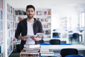 portrait of student while reading book  in school library photo