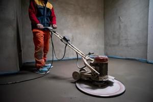 worker performing and polishing sand and cement screed floor photo