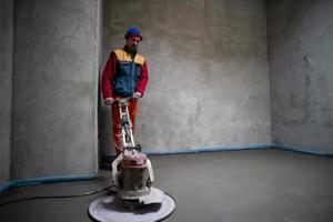 worker performing and polishing sand and cement screed floor photo