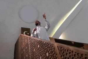 el joven imán árabe musulmán tiene un discurso en la oración del viernes por la tarde en la mezquita. foto