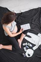 top view of pregnant woman checking list of baby clothes photo