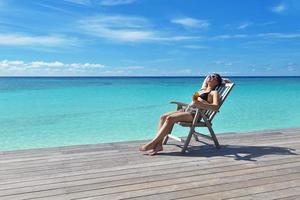 Beautiful young woman with a drink by the sea photo