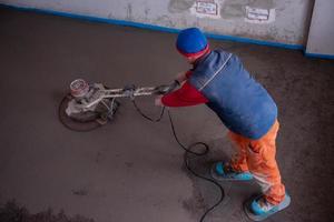 trabajador realizando y puliendo suelo de solera de cemento y arena foto