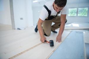 Professional Worker Installing New Laminated Wooden Floor photo