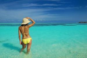 mujer asiática descansando sobre la arena en la playa foto