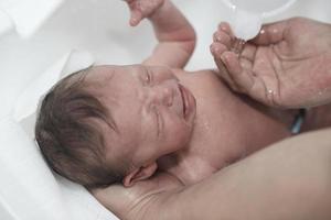 Newborn baby girl taking a first bath photo