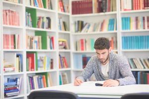 portrait of student while reading book  in school library photo