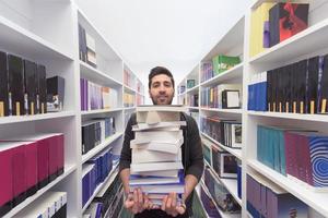 Student holding lot of books in school library photo