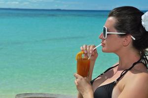 Beautiful young woman with a drink by the sea photo
