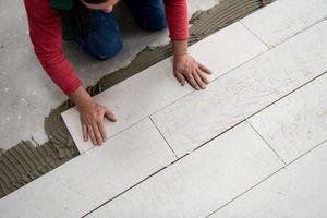 worker installing the ceramic wood effect tiles on the floor photo