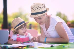 mamá y su pequeña hija dibujando imágenes coloridas foto