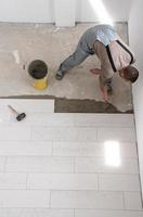 worker installing the ceramic wood effect tiles on the floor photo