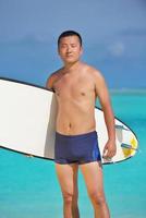 hombre con tabla de surf en la playa foto