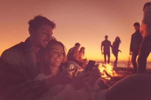 Couple enjoying bonfire with friends on beach photo