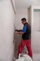 trabajador de la construcción perforando agujeros en el baño foto