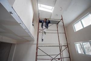 trabajador de la construcción enyesado en el techo de yeso foto