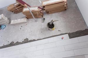 Baldosas cerámicas con efecto de madera y herramientas para baldosas en el suelo. foto