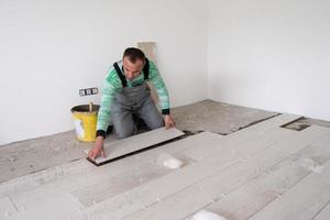 worker installing the ceramic wood effect tiles on the floor photo