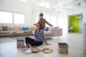 madre e hija pequeña jugando con joyas en casa foto