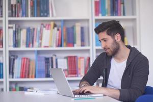 student in school library using laptop for research photo