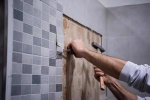 trabajador quitar demoler azulejos viejos en un baño foto