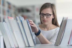 portrait of famale student selecting book to read in library photo