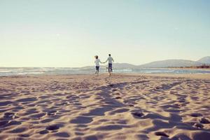 couple with dog having fun on beach on autmun day photo