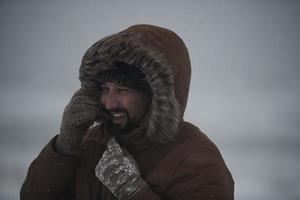 hombre en invierno en clima tormentoso con chaqueta de piel caliente foto