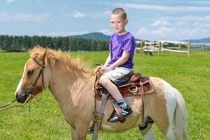 niño montar pony foto