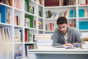 portrait of student while reading book  in school library photo