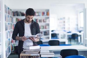 portrait of student while reading book  in school library photo