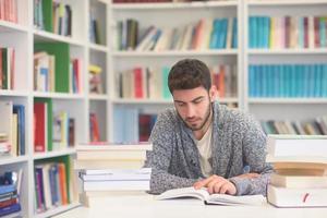 portrait of student while reading book  in school library photo