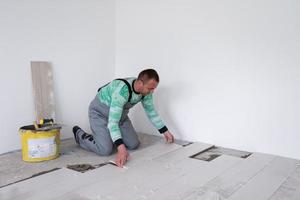 worker installing the ceramic wood effect tiles on the floor photo