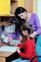 mom and girl doing homework at home photo