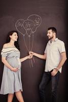 pareja embarazada dibujando su imaginación en una pizarra
