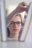 portrait of famale student selecting book to read in library photo