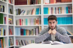 portrait of student while reading book  in school library photo