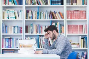 portrait of student while reading book  in school library photo