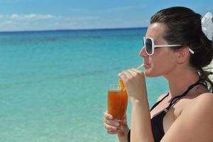 Beautiful young woman with a drink by the sea photo